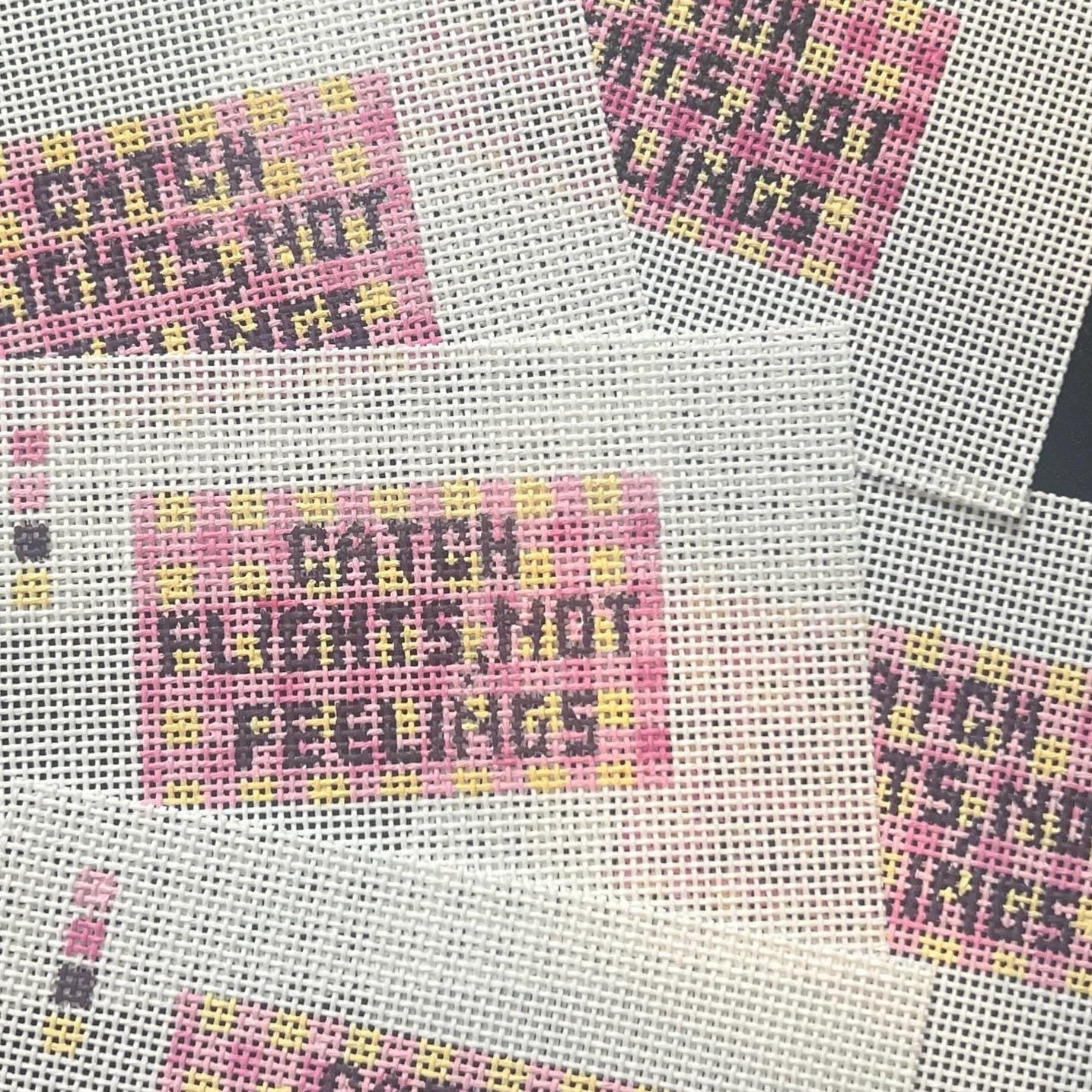 Catch flights not feelings needlepoint on a gingham background
