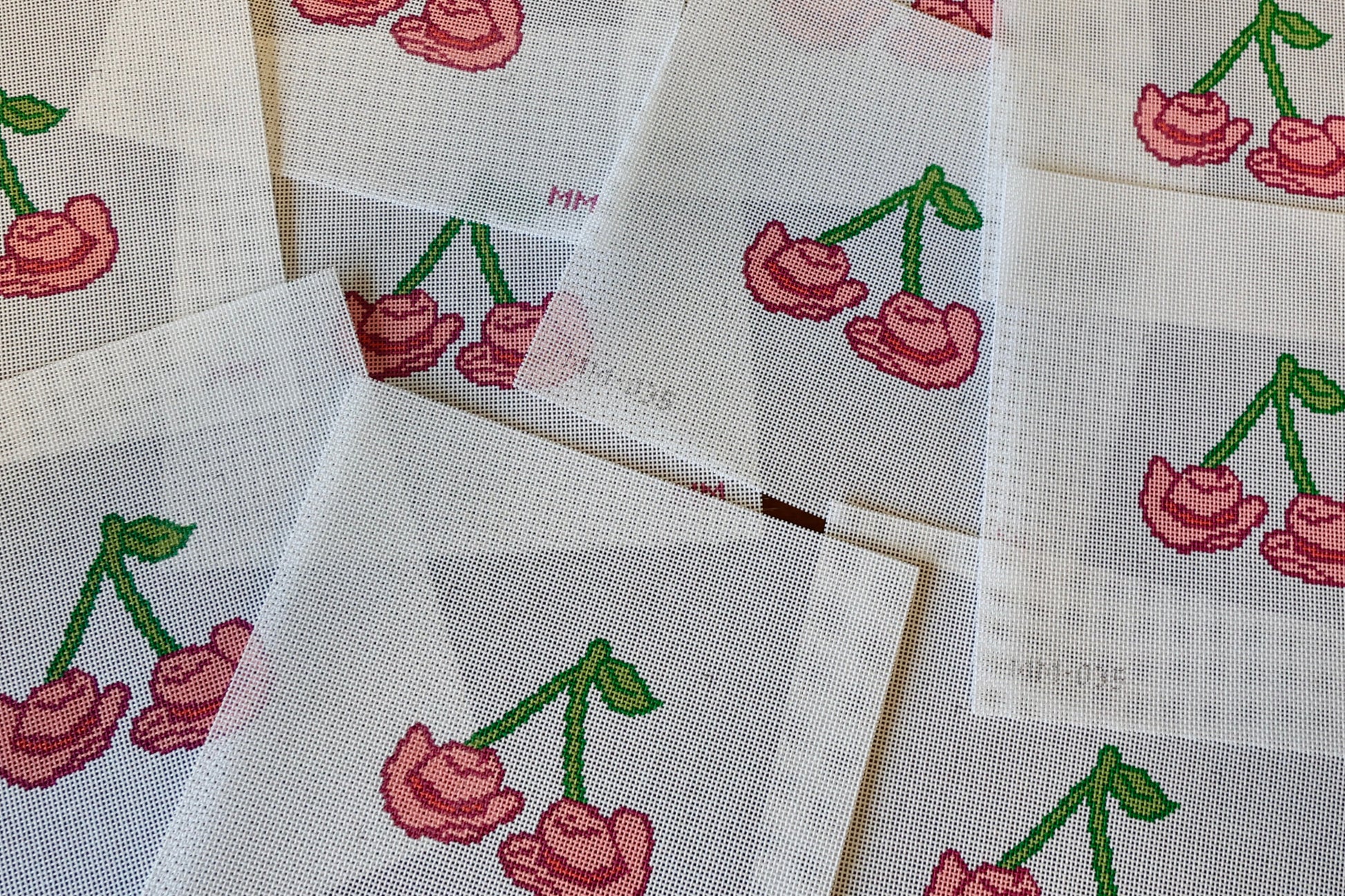 Needlepoint with cherry cowboy hat designs on a wooden surface
