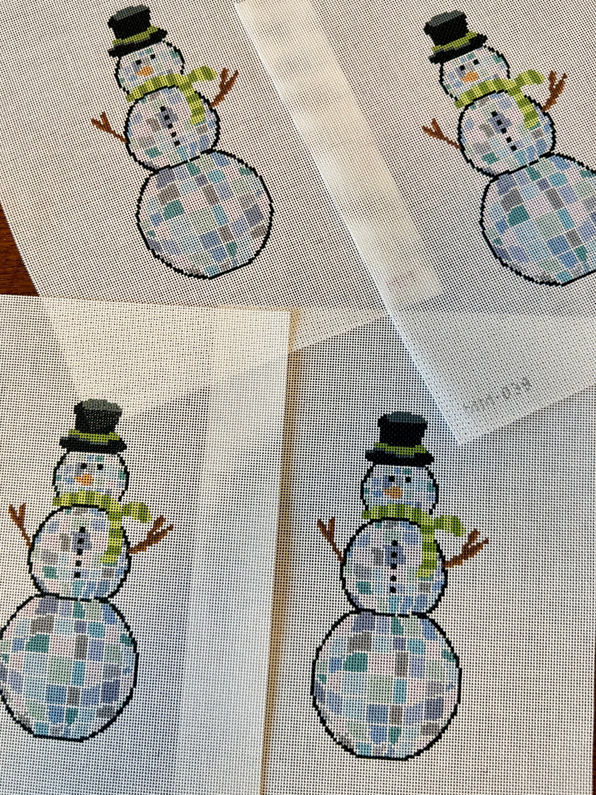 Needlepoint snowmen on fabric with a wooden surface background